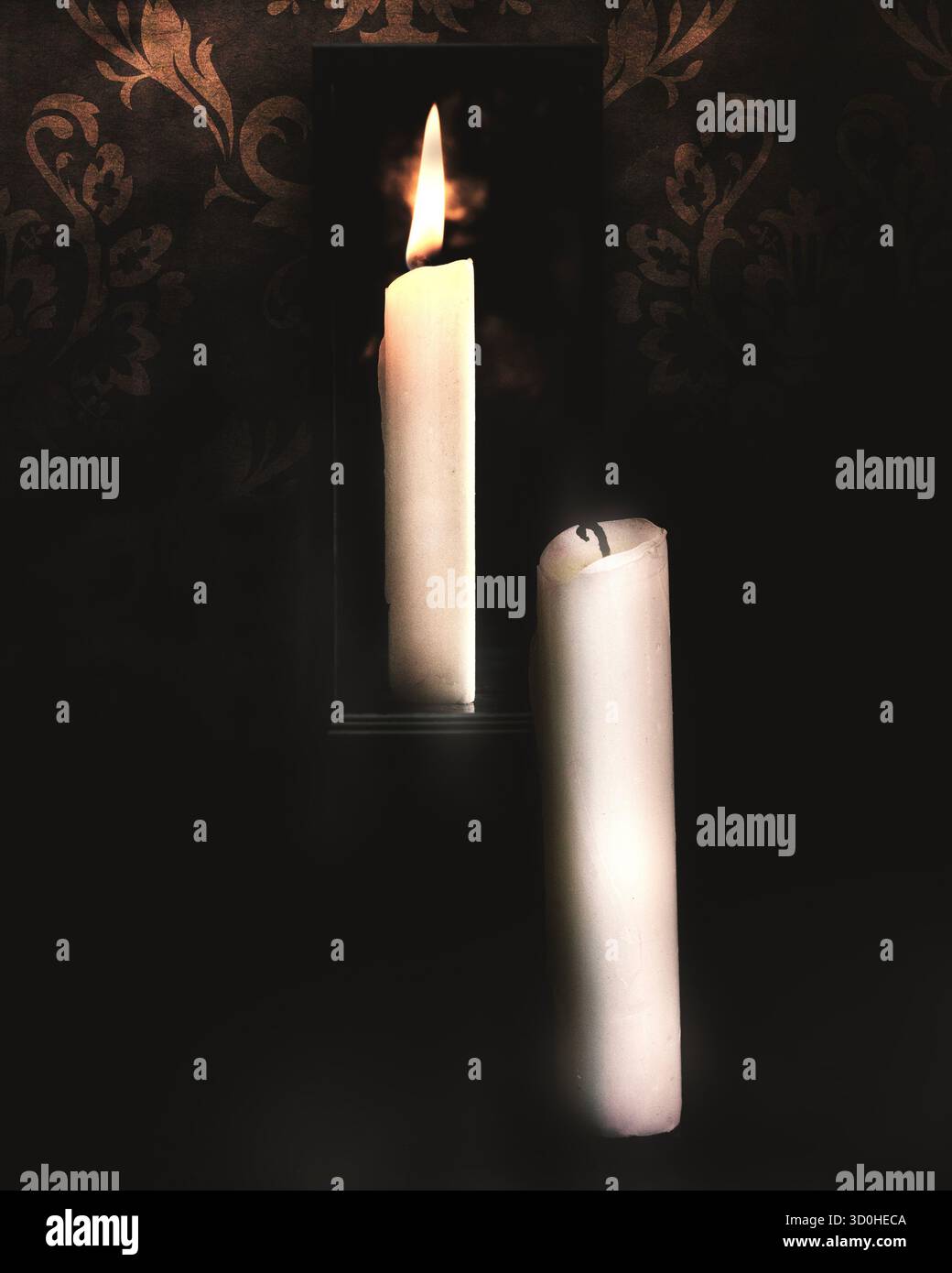 A candle with no flame reflected in a mirror showing a flame in the mirror. - Stock Image