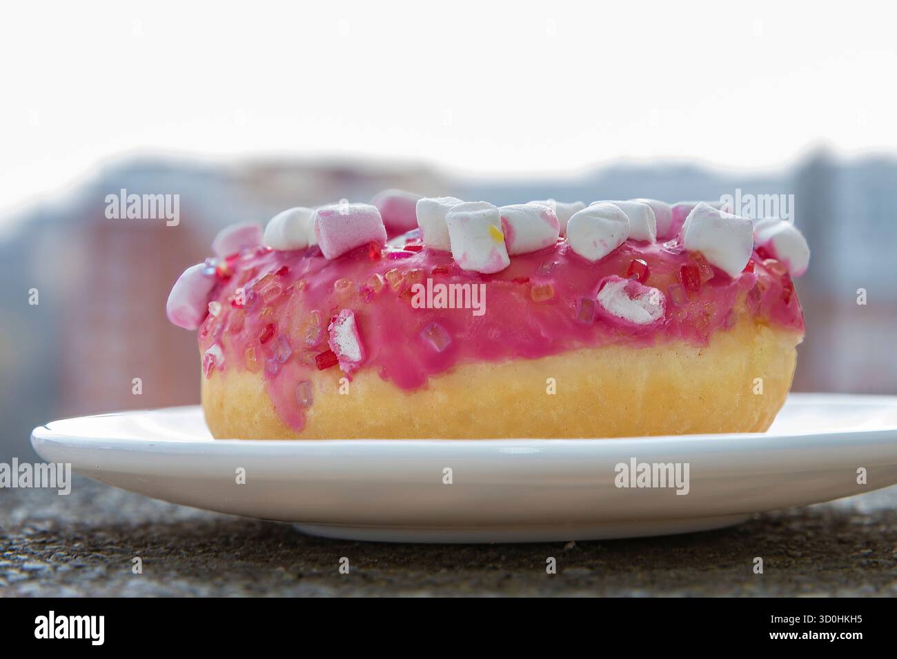 Pink donut with marshmallows on white plate Stock Photo