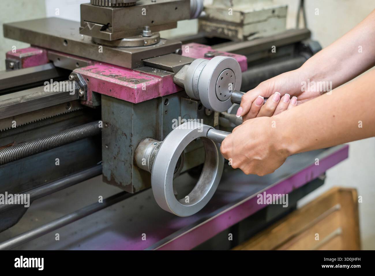 Woman operator using manual controls on metal lathe machine Stock Photo