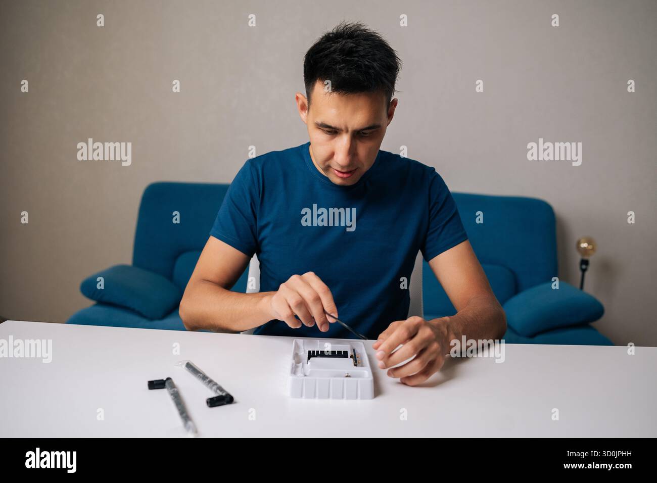 Portrait of technician male assembling wi-fi module using specialized tools at home office desk, focusing on intricate components and ensuring proper Stock Photo