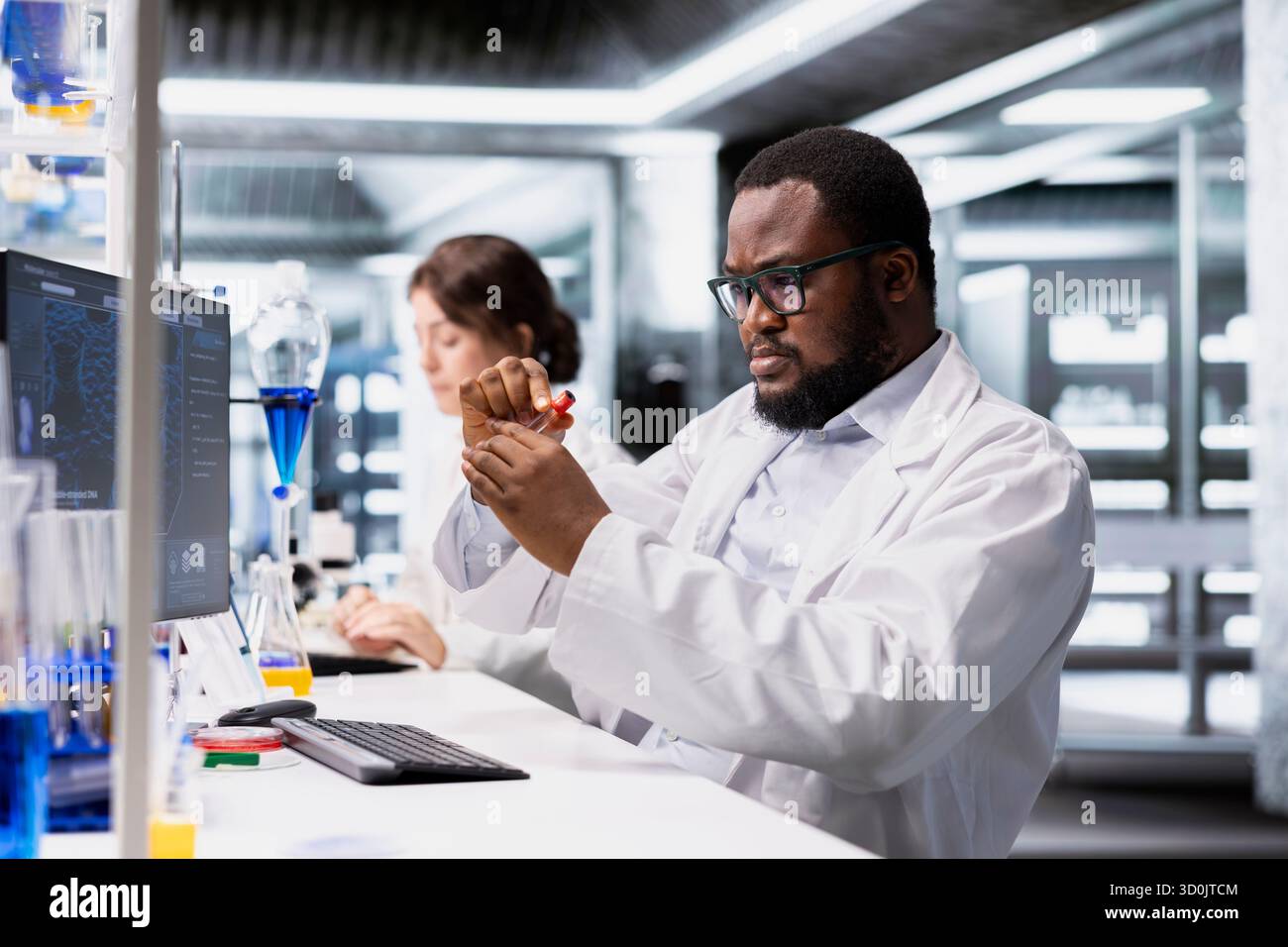 Chemical engineer in lab inspecting chemical compound clarity in vials ...