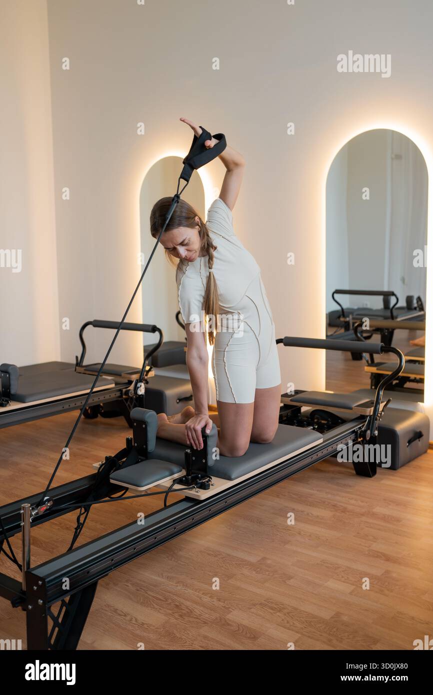 Female adjusting reformer exercises, Woman performing Pilates exercises ...