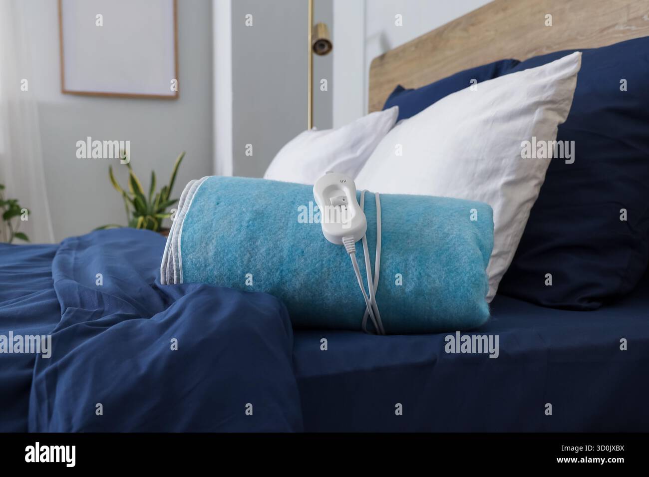 Folded electric heating pad on bed in room Stock Photo