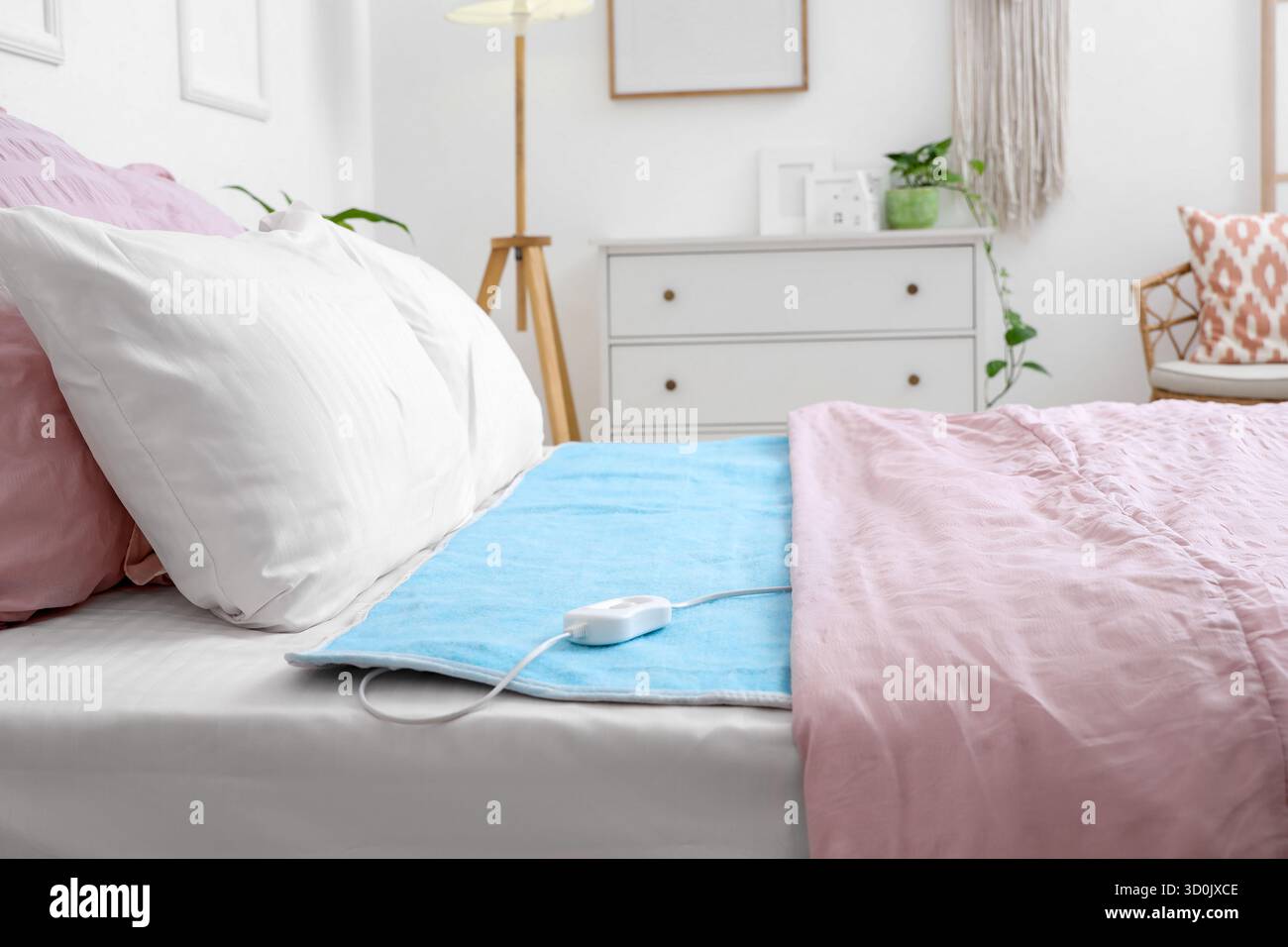 Modern electric heating pad on bed in room Stock Photo