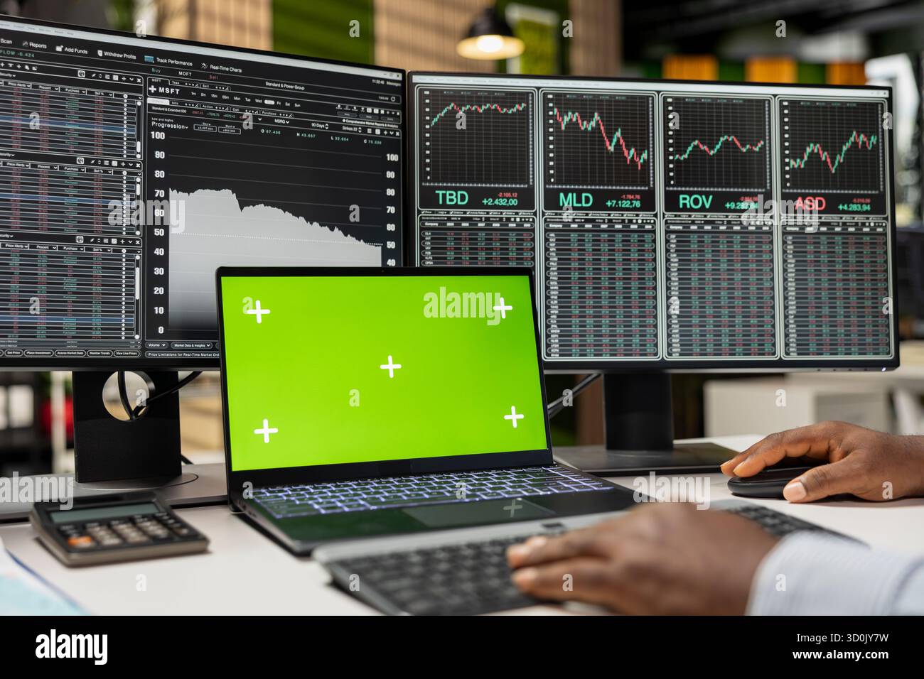 Close up of prop firm trader using green screen laptop on desk and computer displaying stock market candlestick graphs. Financial expert uses chroma key notebook and PC showing stock exchange assets Stock Photo