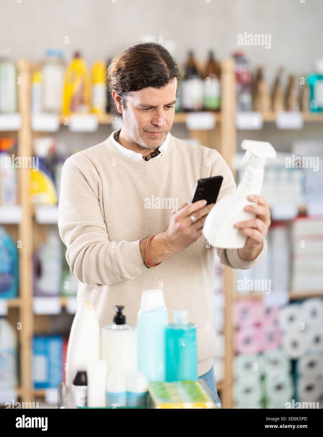 Middle-aged man scanning spray barcode in store Stock Photo