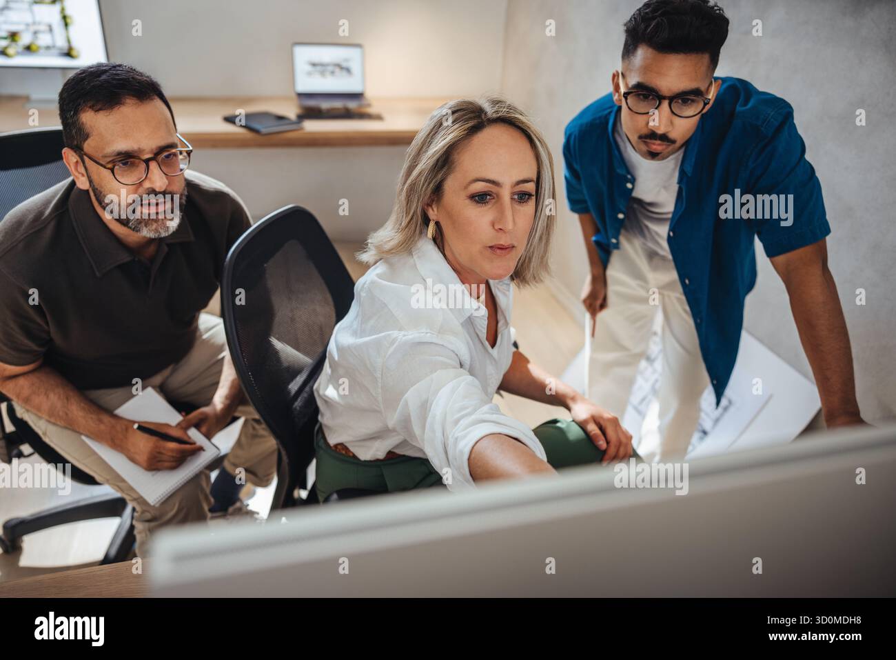 Three architects engaging in a creative discussion, showcasing teamwork and design process. Stock Photo