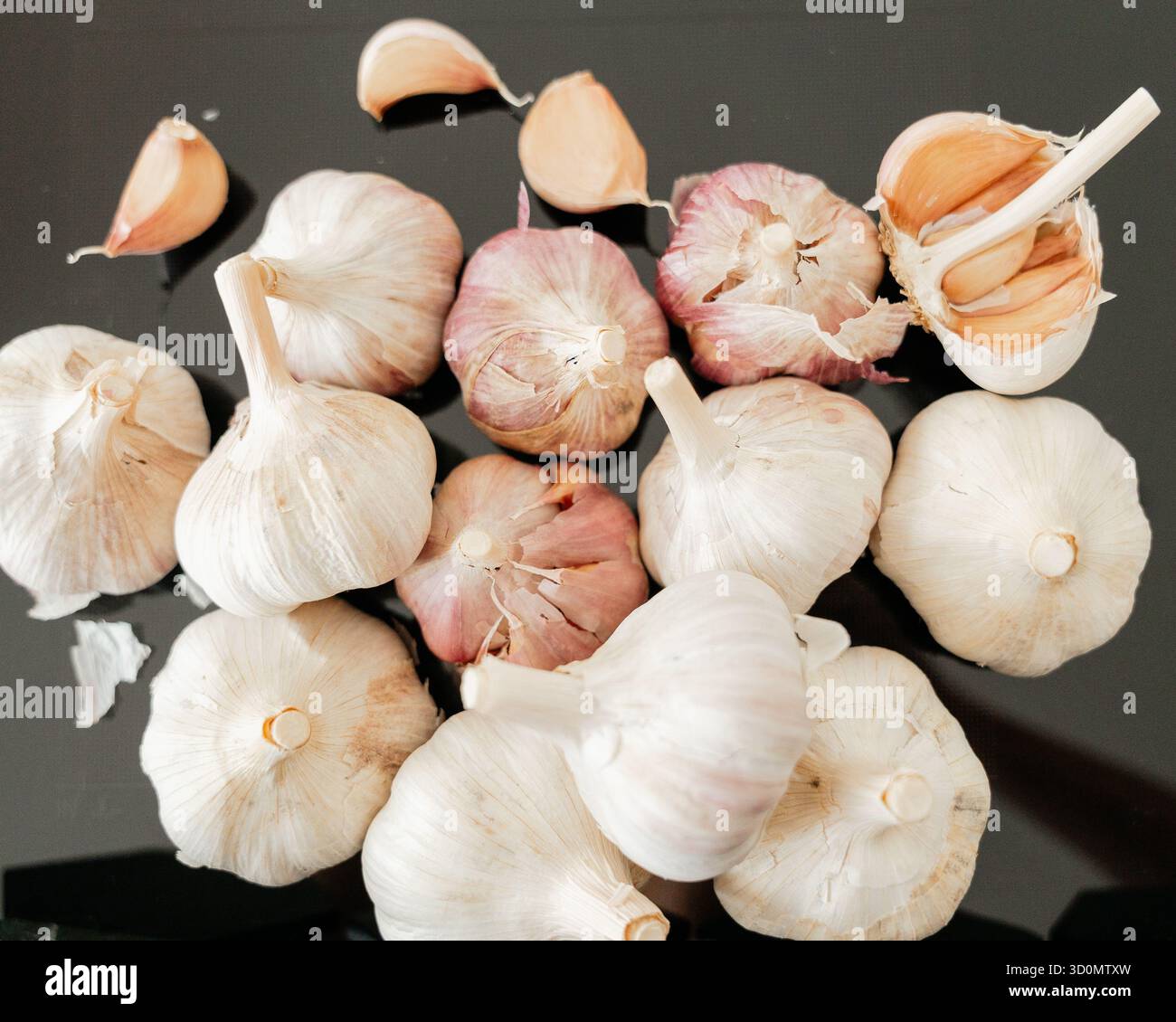 Group of garlic heads and loose cloves on dark background with natural ...