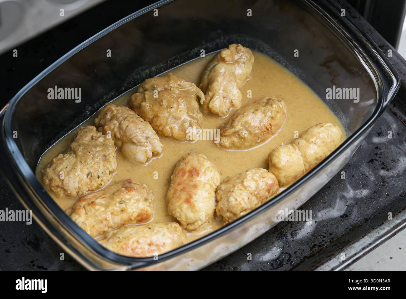 Beef roulades baking in oven dish with sauce. Traditional homemade dinner preparation. Glass baking dish inside oven. Comfort food concept. Stock Photo