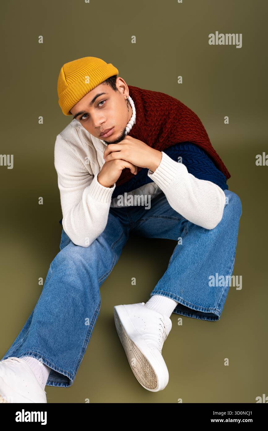 A handsome young man sits confidently in stylish attire, embodying ...