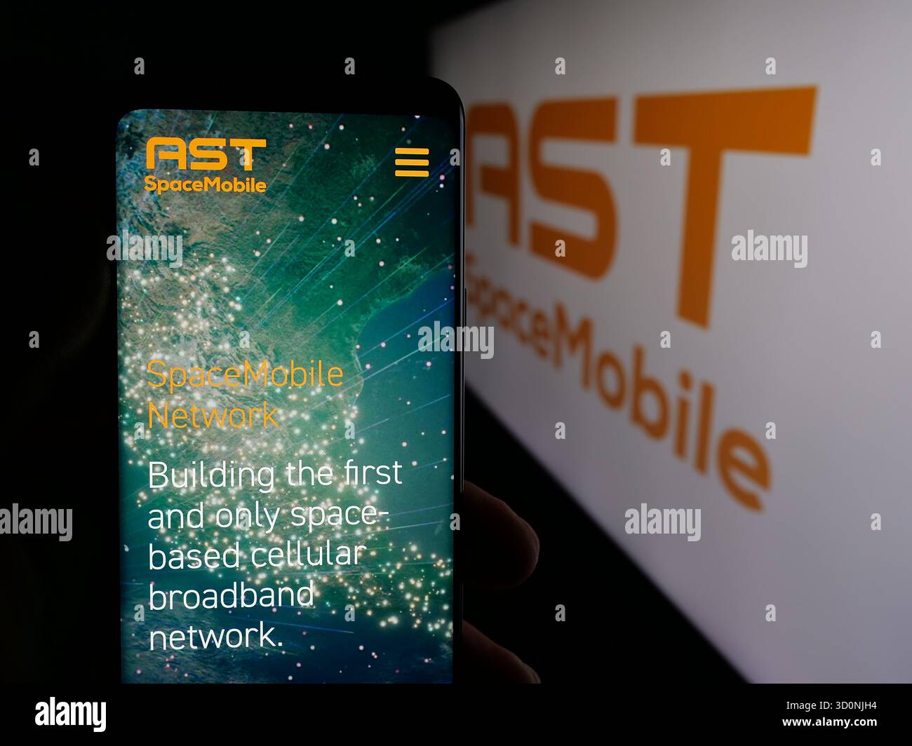 Stuttgart, Germany - 10-18-2025: Person holding cellphone with webpage of US satellite company AST SpaceMobile Inc. on screen in front of logo. Focus Stock Photo