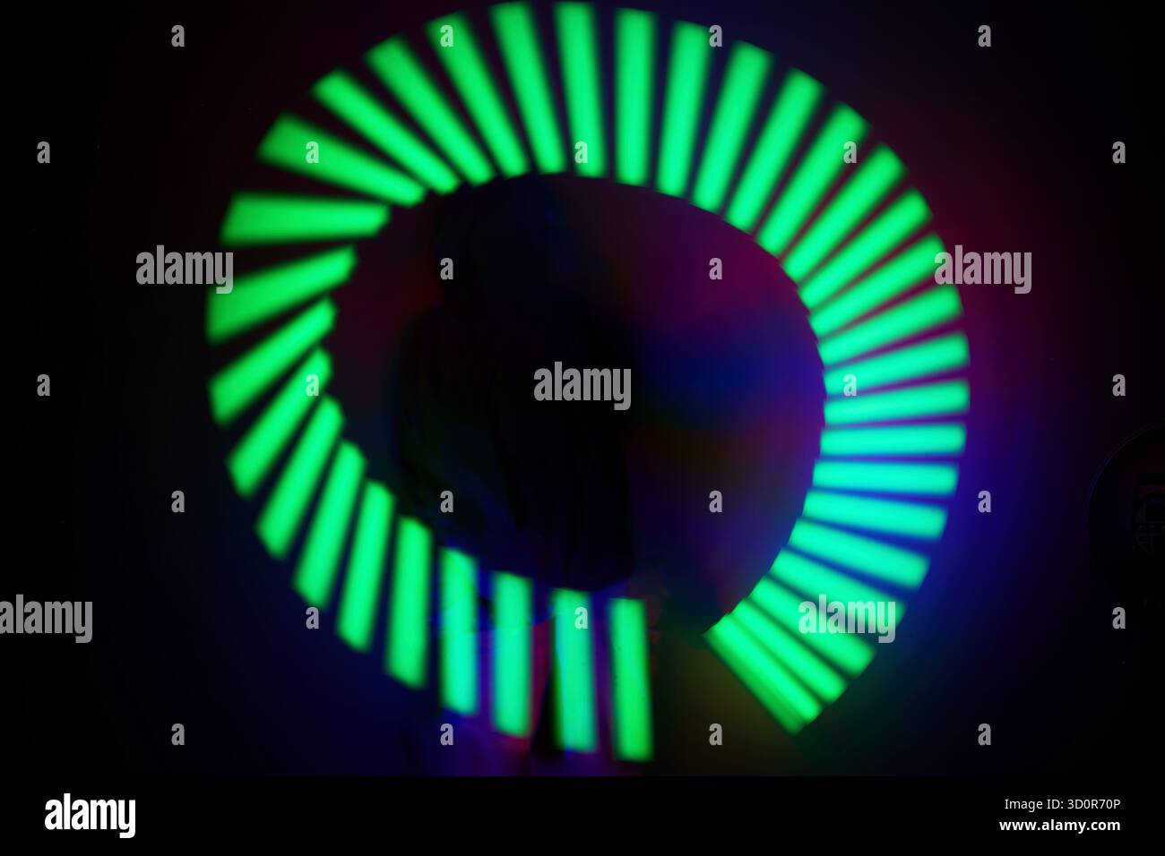 Neon Light Spiral. A vibrant spiral of neon green and blue lights with a dark background. Stock Photo