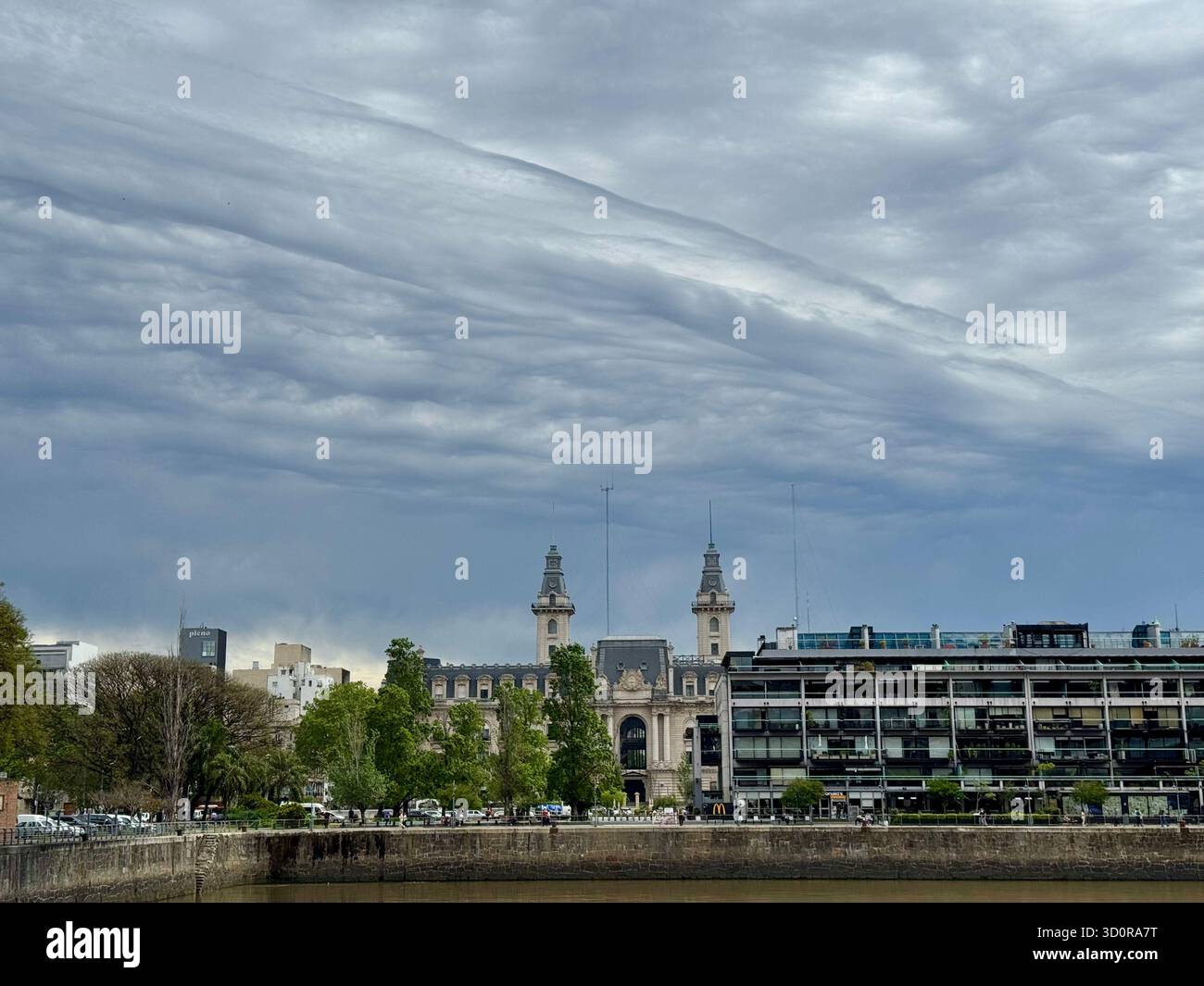Historic building with twin spires and ornate architecture stands along the waterfront in Buenos Aires, Argentina, framed by a modern glass building u - Smartphone Captured Stock Image