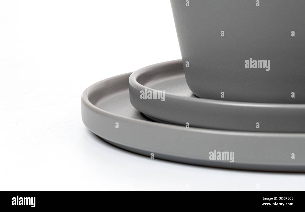 Grey ceramic tableware set, including plates and cup, stacked on a clean white surface Stock Photo