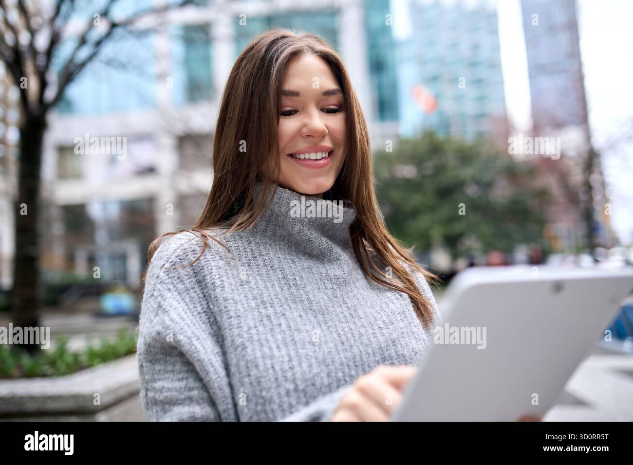 Young busy business woman standing in city using digital tablet. Stock Photo