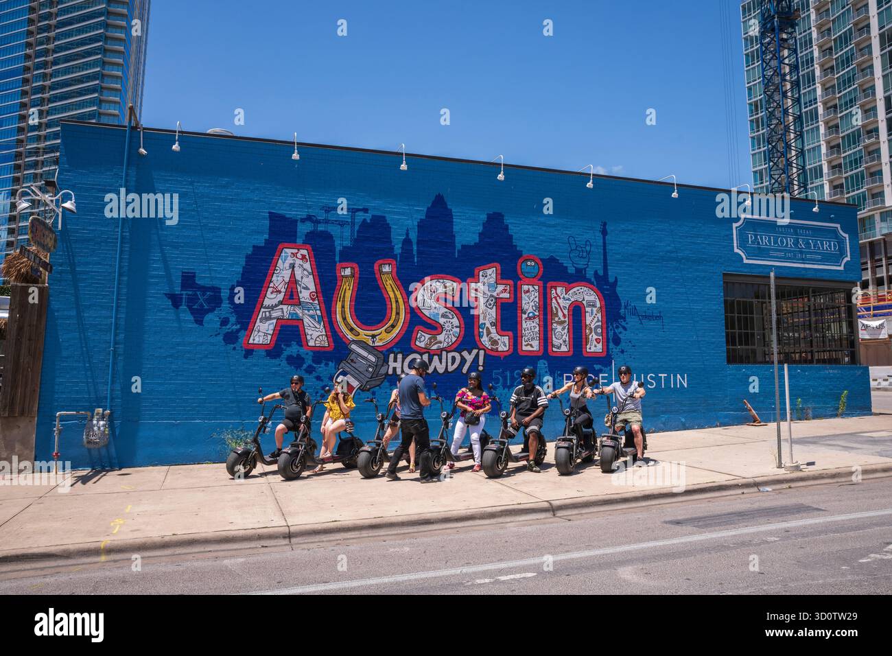 Austin, TX USA - May 2, 2019: E-bike tour group poses with the Austin Howdy mural in Downtown Austin. Stock Photo