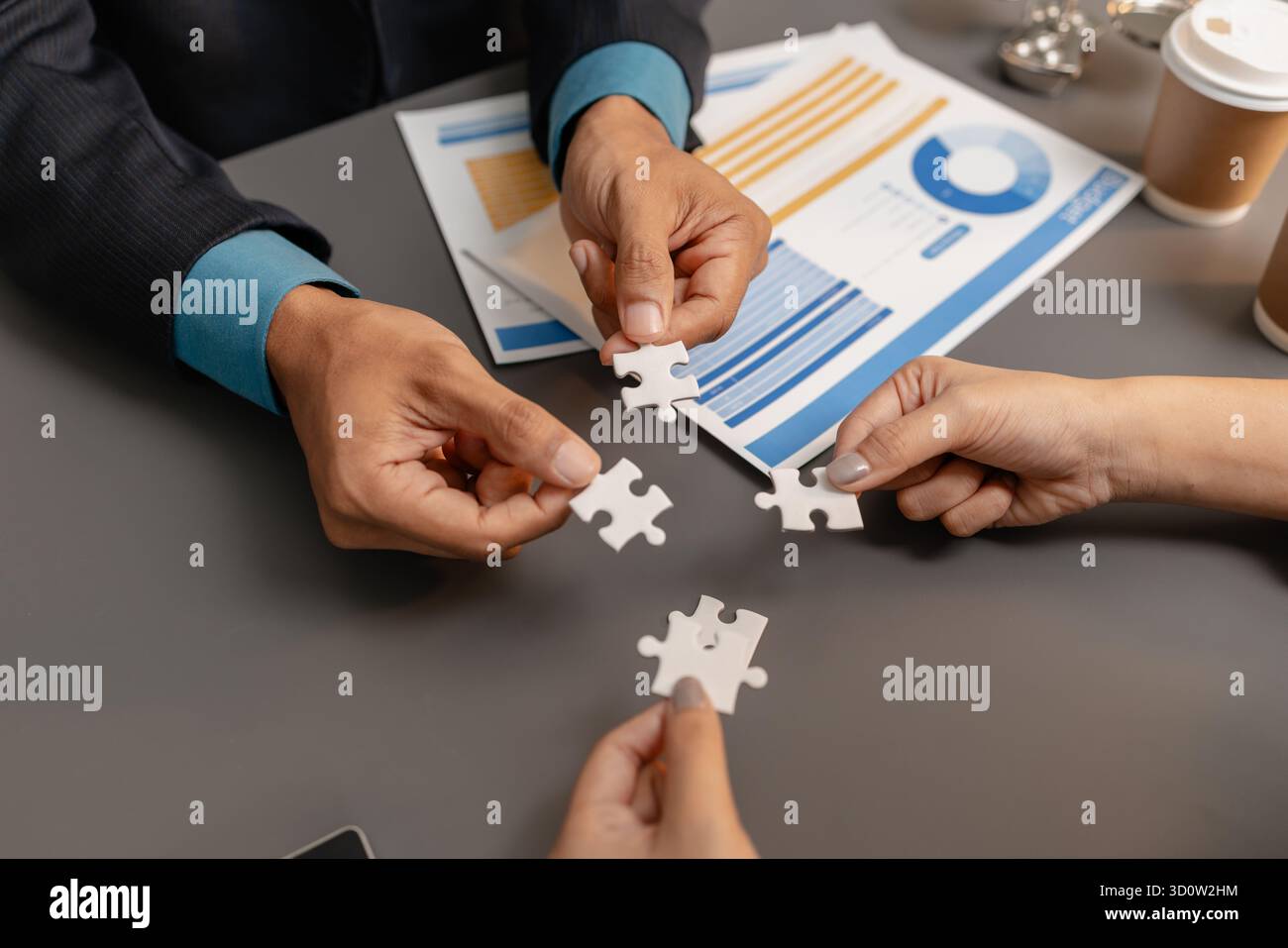 Effecti Business people holding puzzle pieces together on the office desk ...