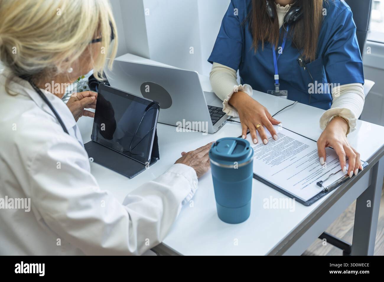 Healthcare team reviewing digital tablet and medical records ...