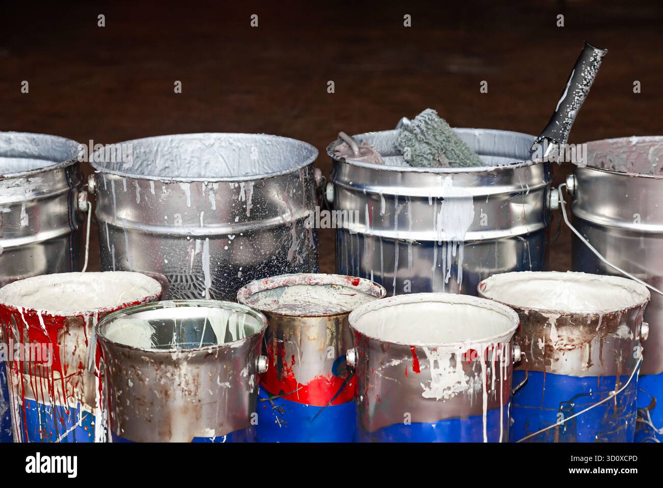 Empty paint buckets containing used rollers and brushes. Stock Photo