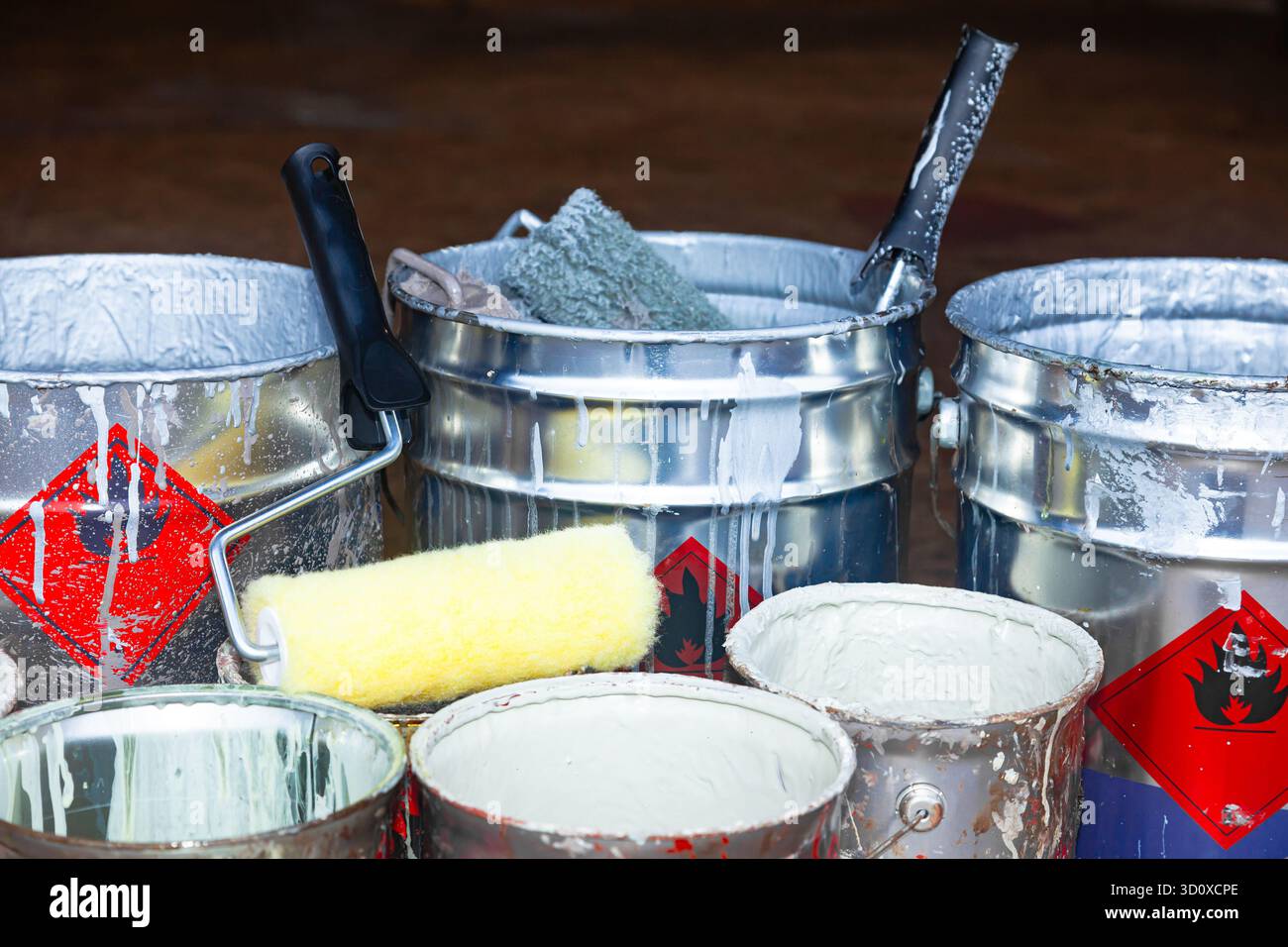 Empty paint buckets containing used rollers and brushes. Stock Photo