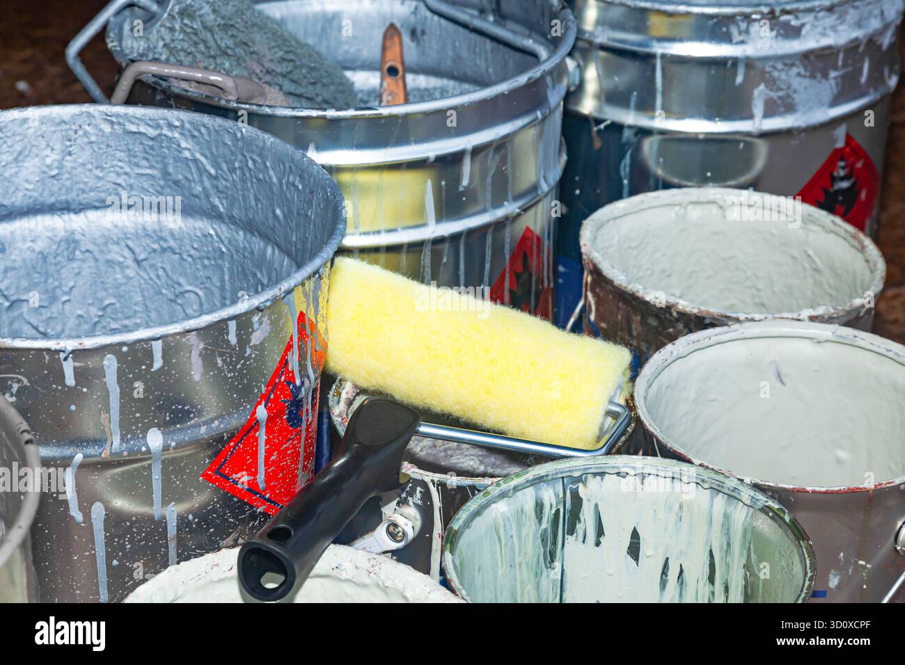 Empty paint buckets containing used rollers and brushes. Stock Photo
