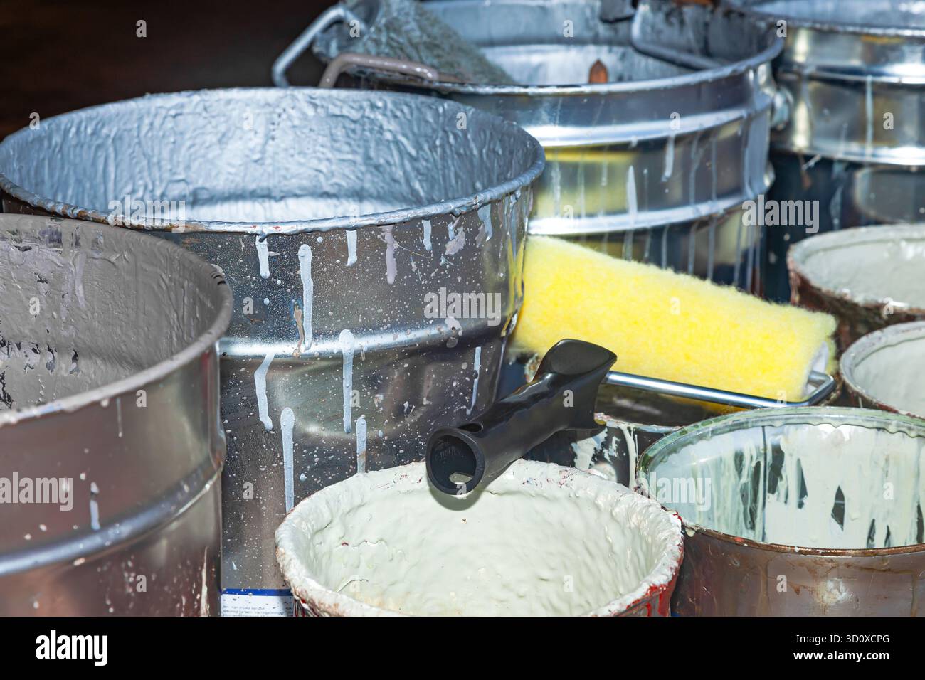 Empty paint buckets containing used rollers and brushes. Stock Photo