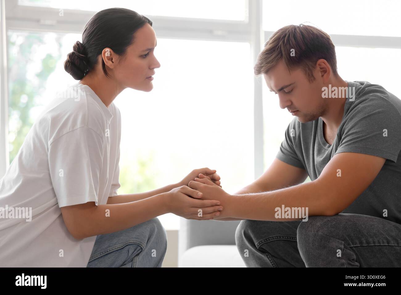 Young woman supporting sad man with suicidal thoughts at home Stock Photo