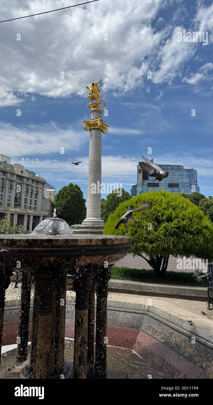 Freedom Monument in Tbilisi with pigeons flying in the foreground, capturing the lively atmosphere of the city and its iconic landmark. - Smartphone Captured Stock Image Freedom Monument in Tbilisi with pigeons flying in the foreground, capturing the lively atmosphere of the city and its iconic landmark. - Smartphone Captured Stock Image