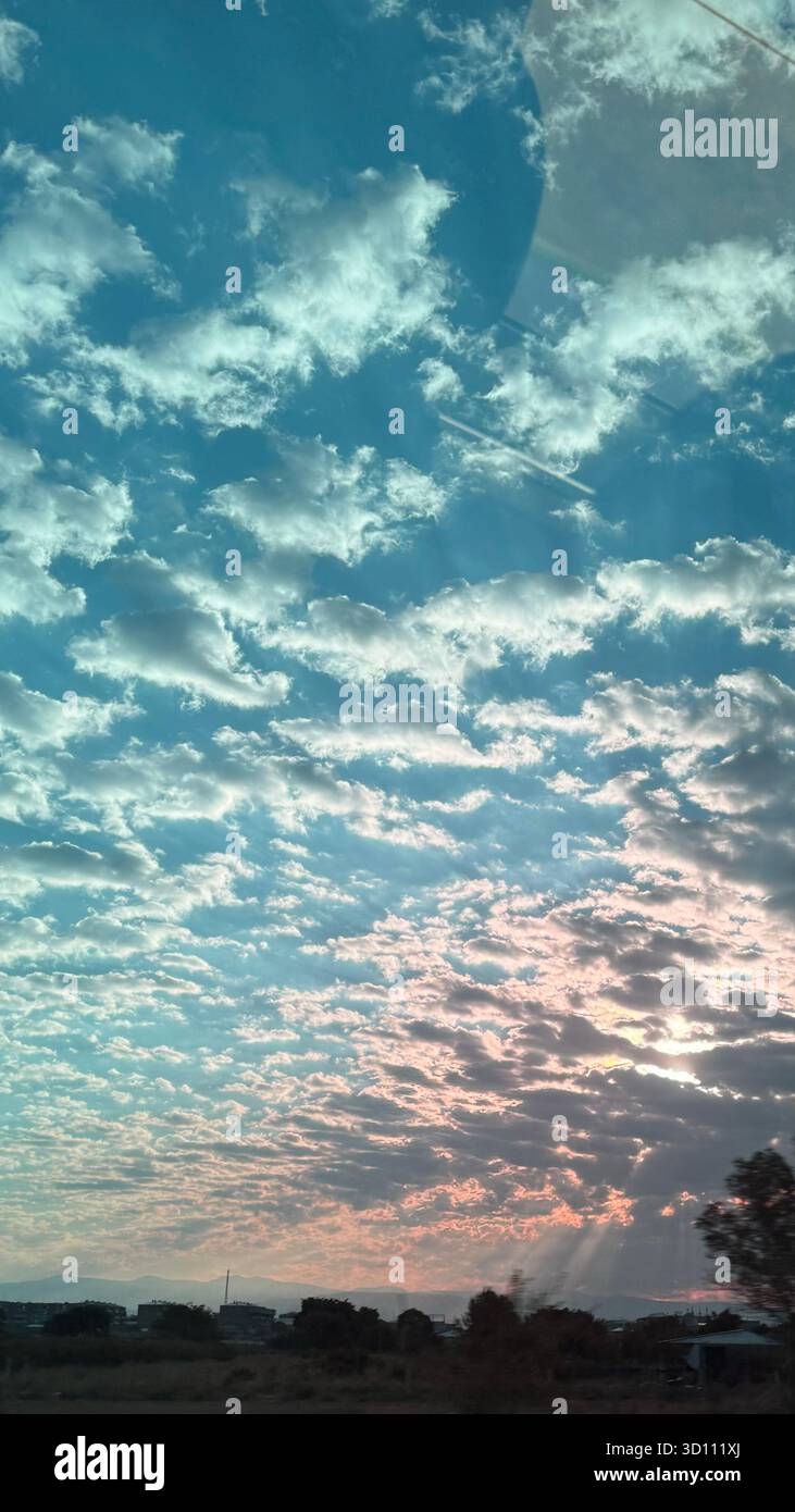 Dramatic sunset sky with clouds, sunlight rays, pastel colors, rural fields, countryside landscape, scenic nature, atmospheric outdoors. - Smartphone Captured Stock Image