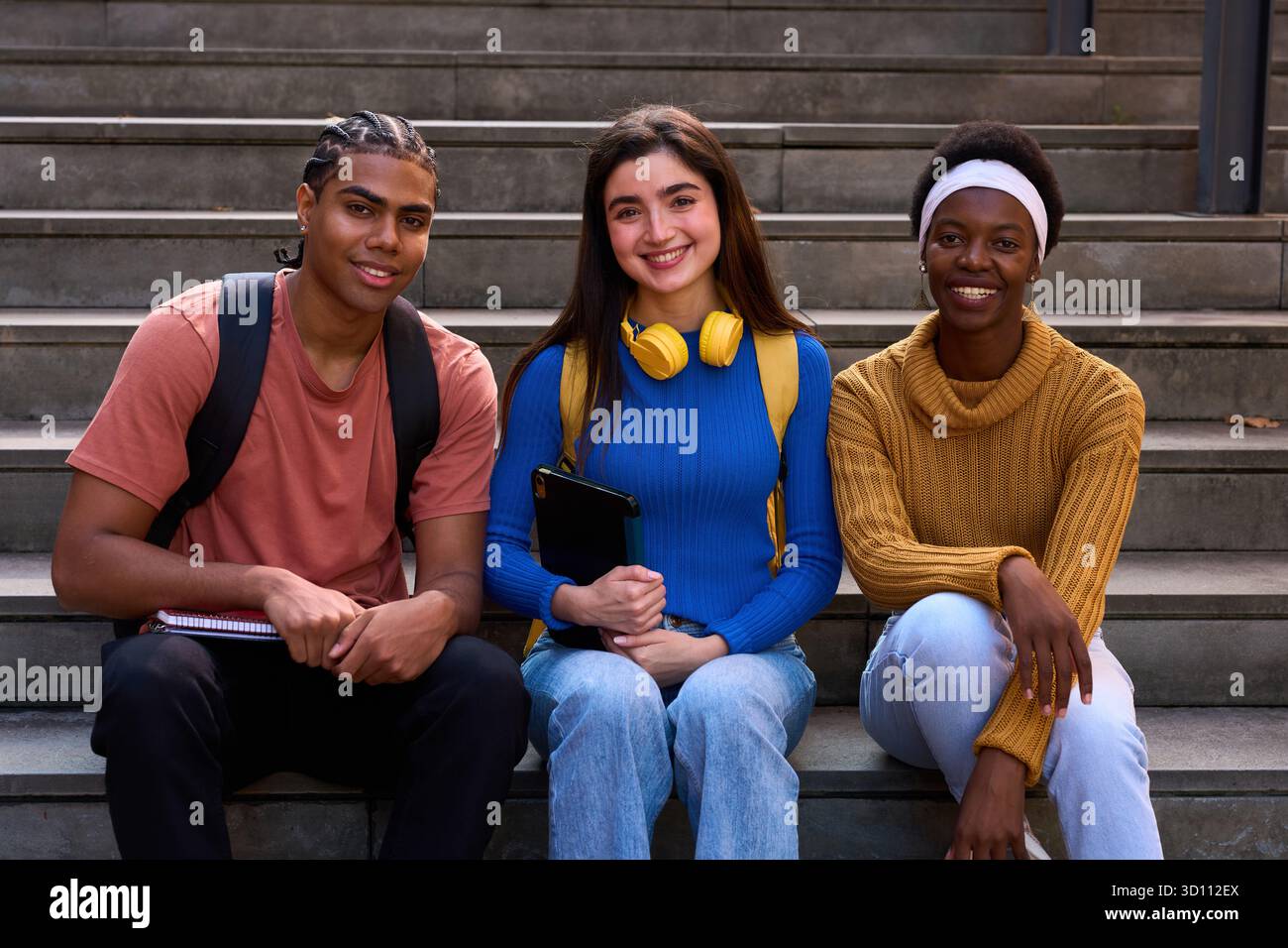 Diverse students sitting on campus stairs smiling Stock Photo