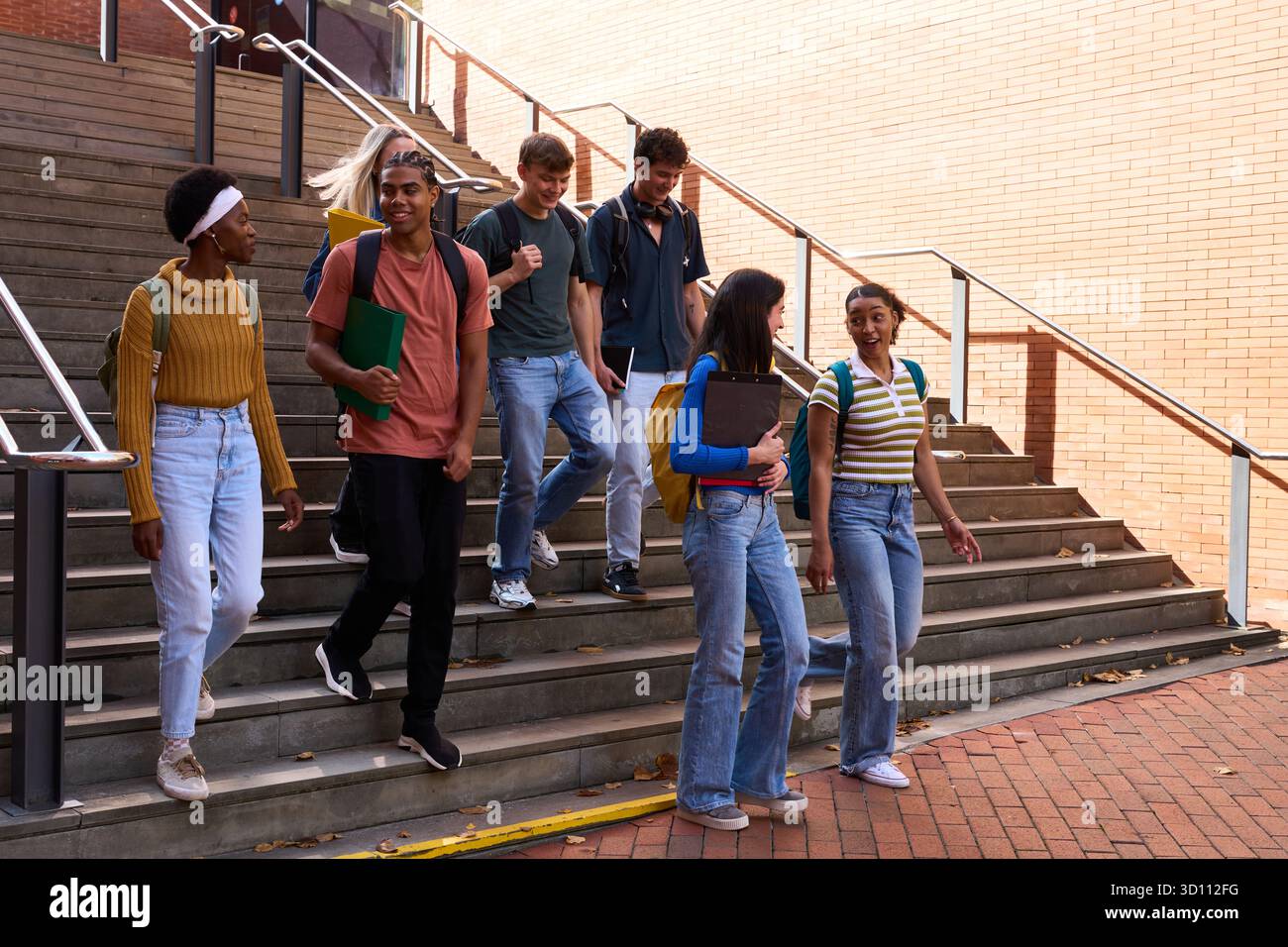 Diverse students walking down university stairs together Stock Photo