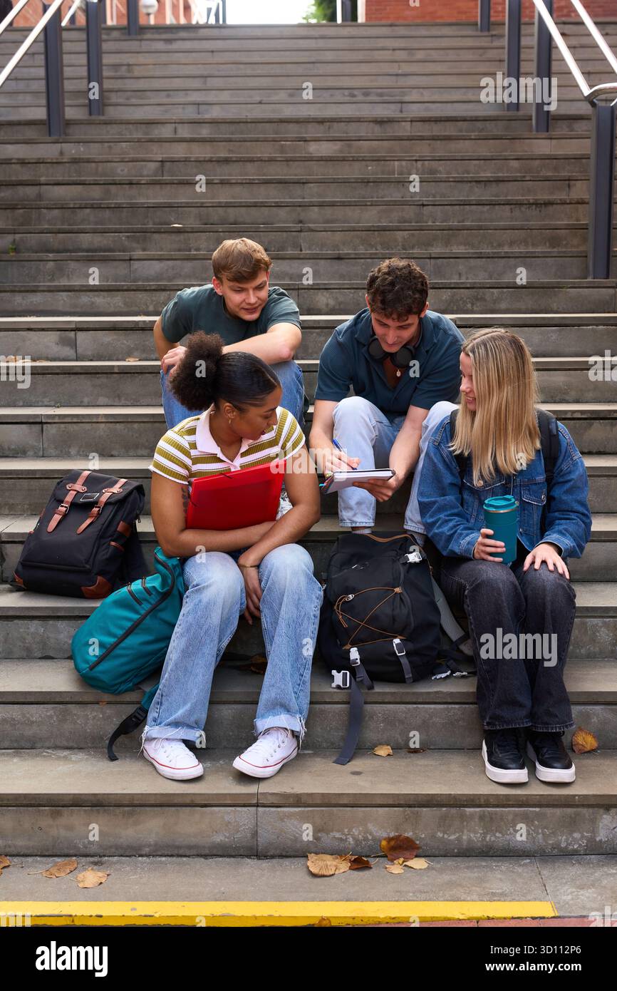 Diverse students collaborating and studying on campus stairs Stock Photo