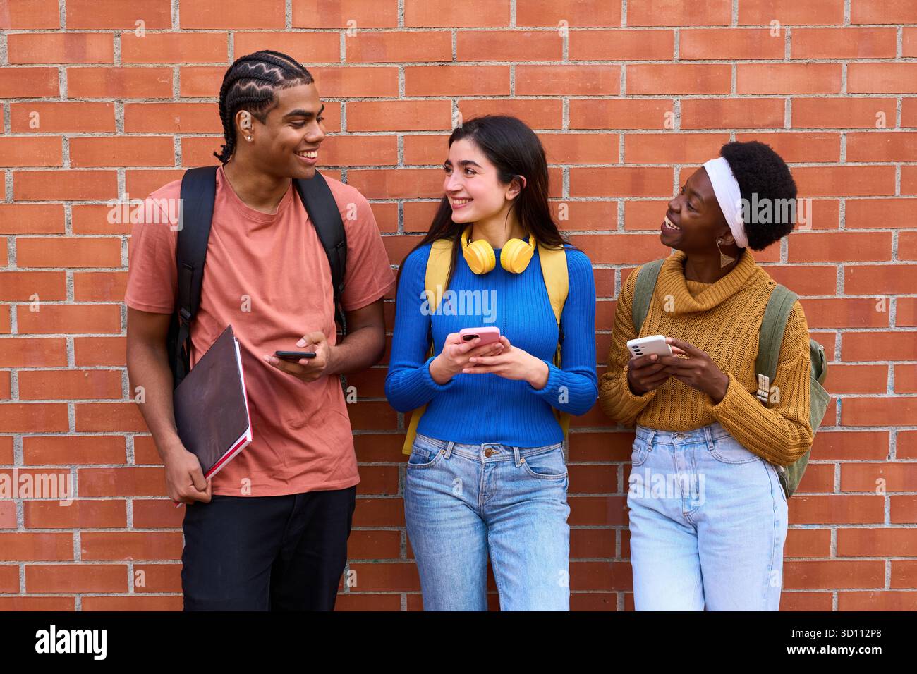 Diverse students using phones, connecting, and smiling Stock Photo