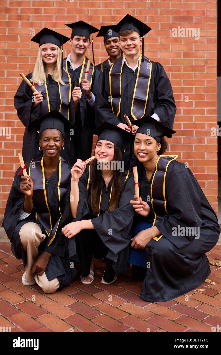 Diverse students celebrating graduation, holding diplomas and smiling Stock Photo