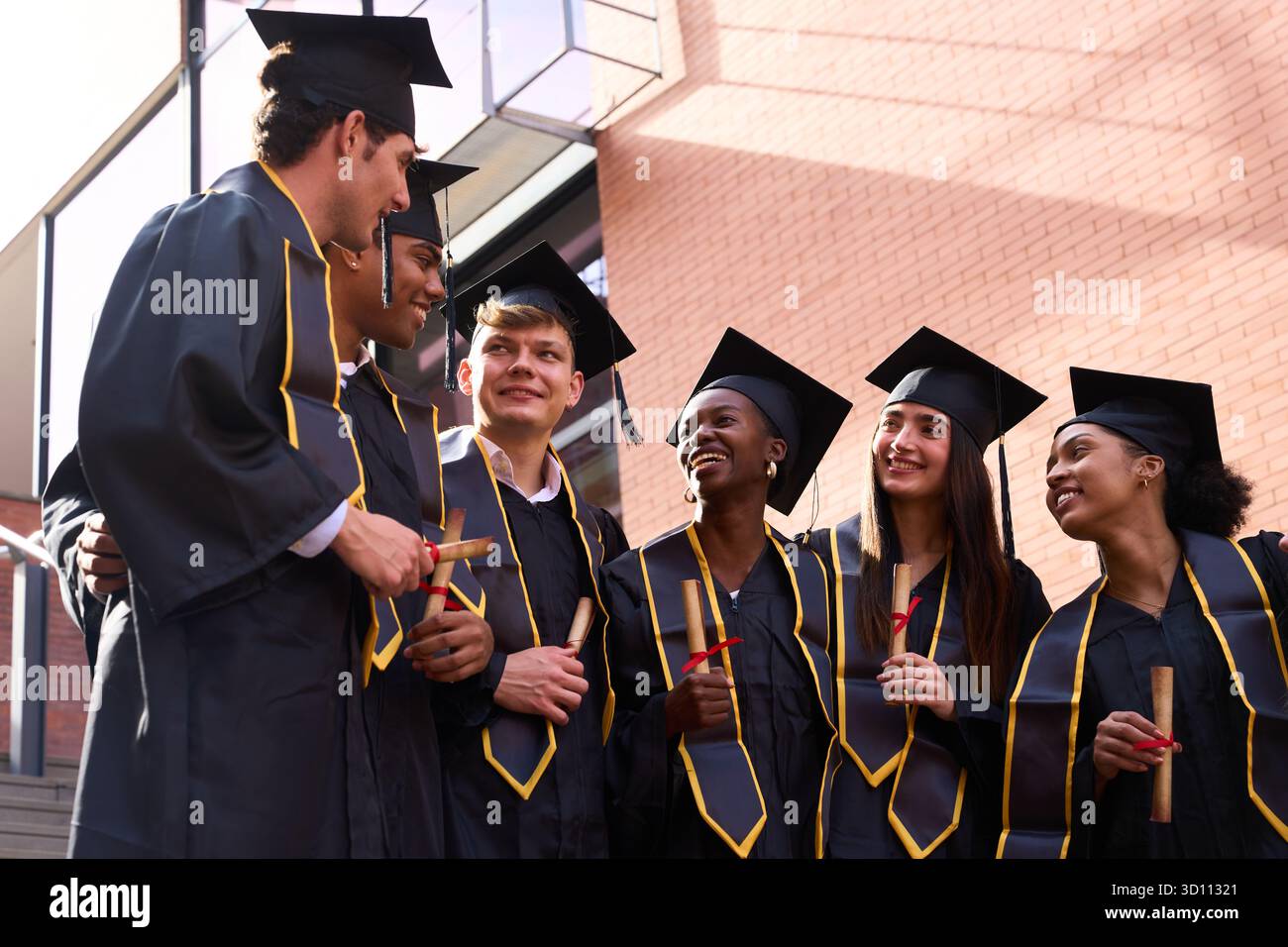 Diverse students celebrating graduation, holding diplomas, and smiling ...