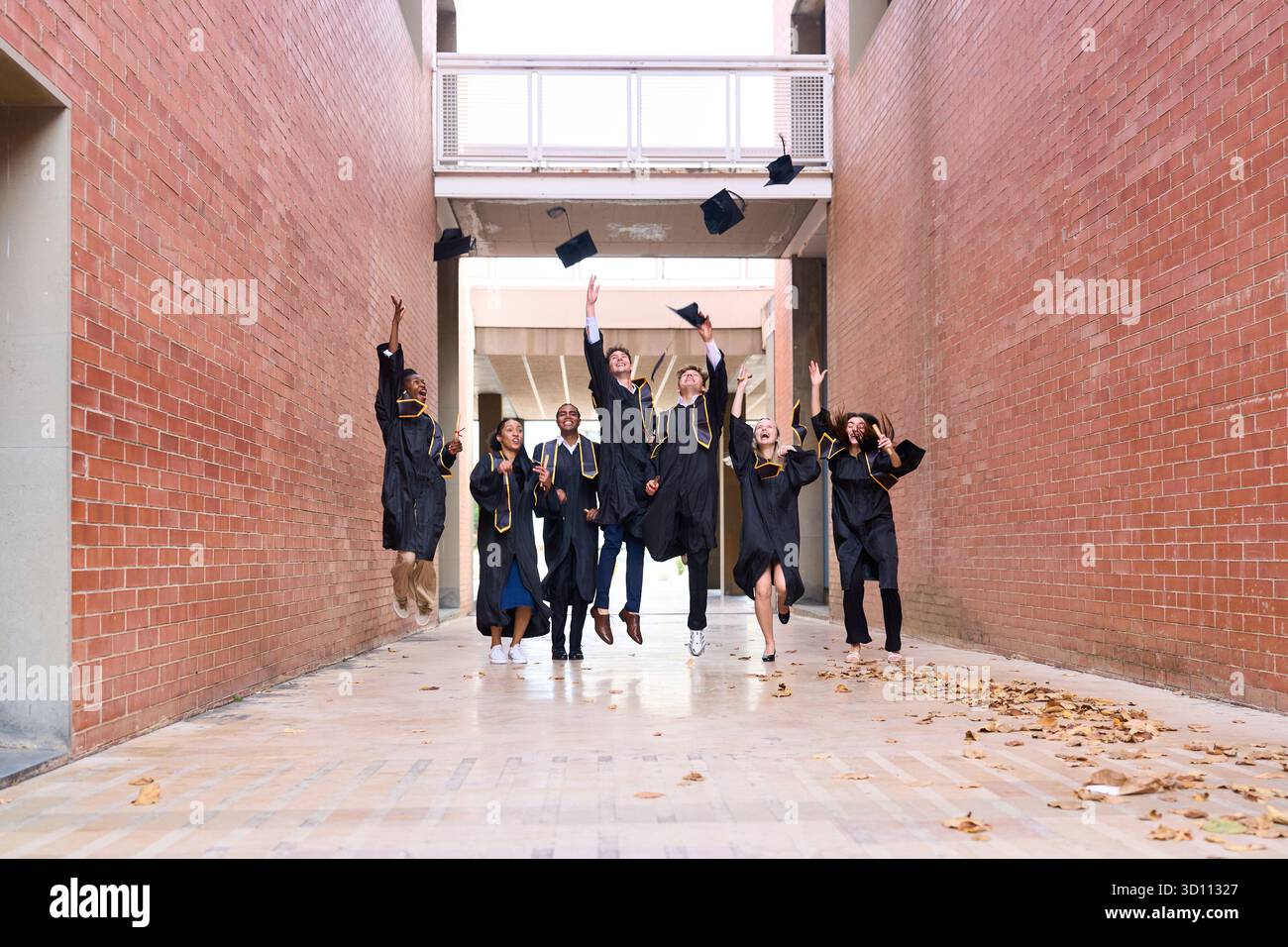 Graduating students jumping and throwing caps in air Stock Photo