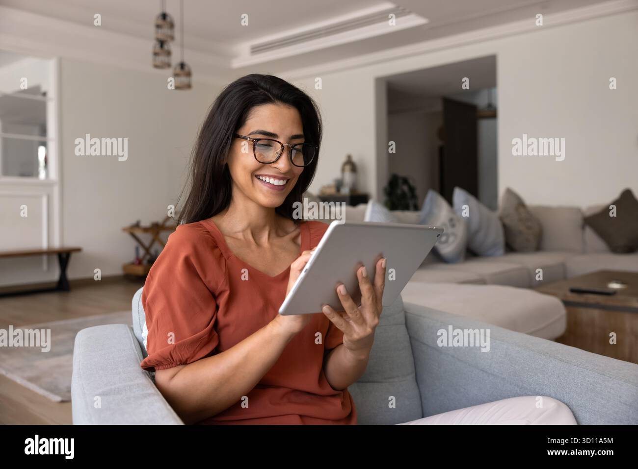 Happy Hispanic gadget user woman using smart application on tablet Stock Photo