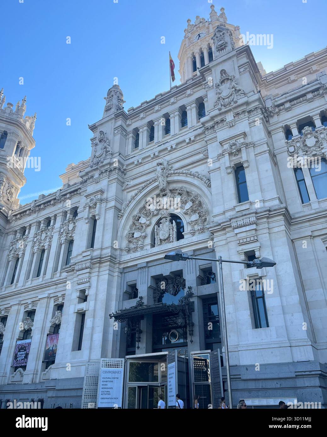 Low-angle view of the Palacio de Cibeles in Madrid, Spain, with the sun shining from behind the building on a bright sunny summer day. - Smartphone Captured Stock Image