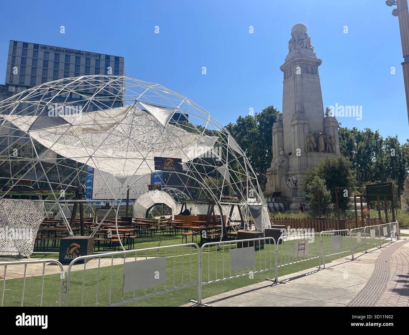 View of the Monumento a Cervantes at Plaza de España in Madrid, Spain, with an Oktoberfest pavilion in the foreground on a sunny summer day. - Smartphone Captured Stock Image
