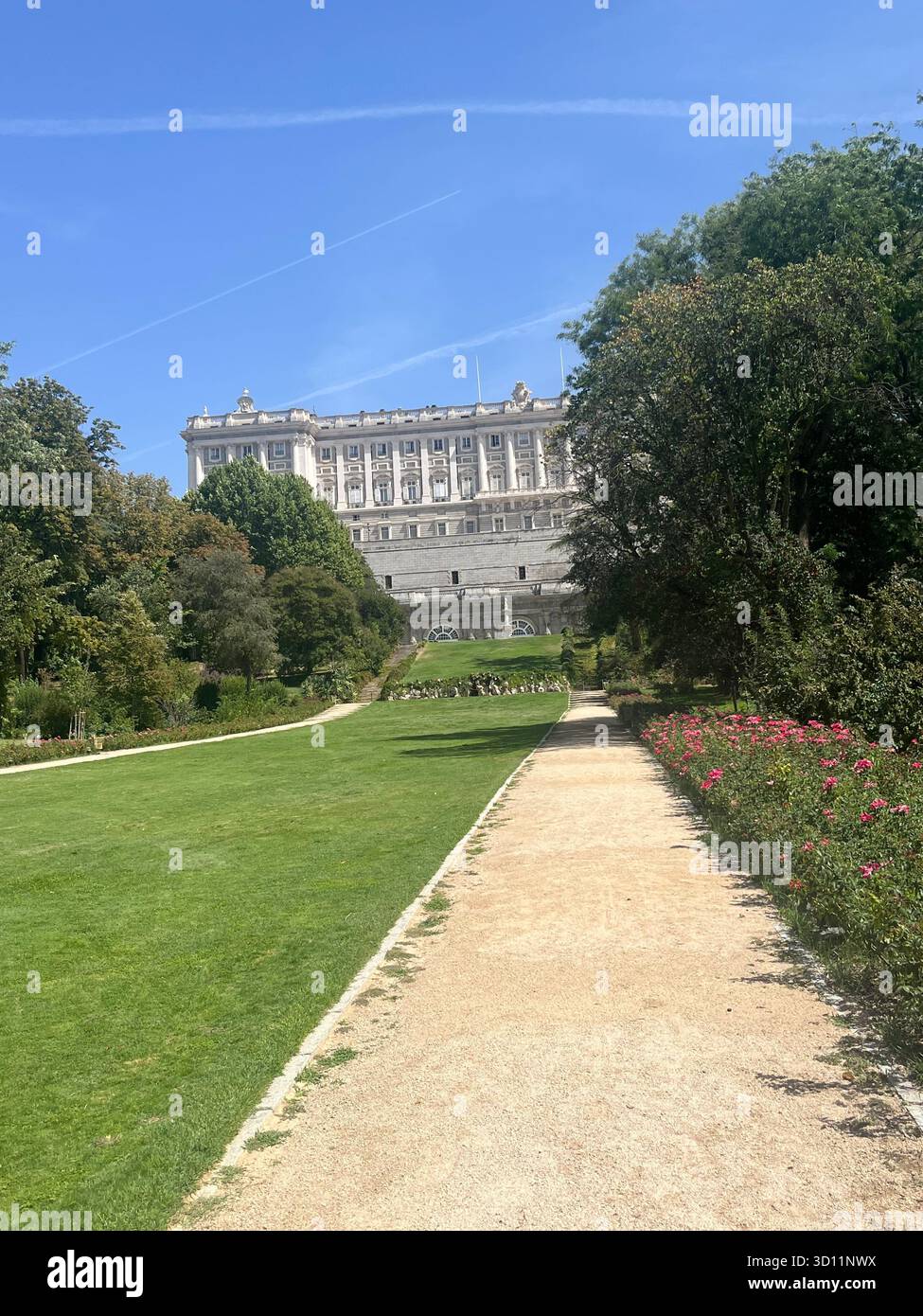 Campo del Moro Gardens with a Scenic View of the Royal Palace in Madrid on a Bright Sunny Summer Day, Featuring Lush Trees, Flowers and Plane Trails. - Smartphone Captured Stock Image