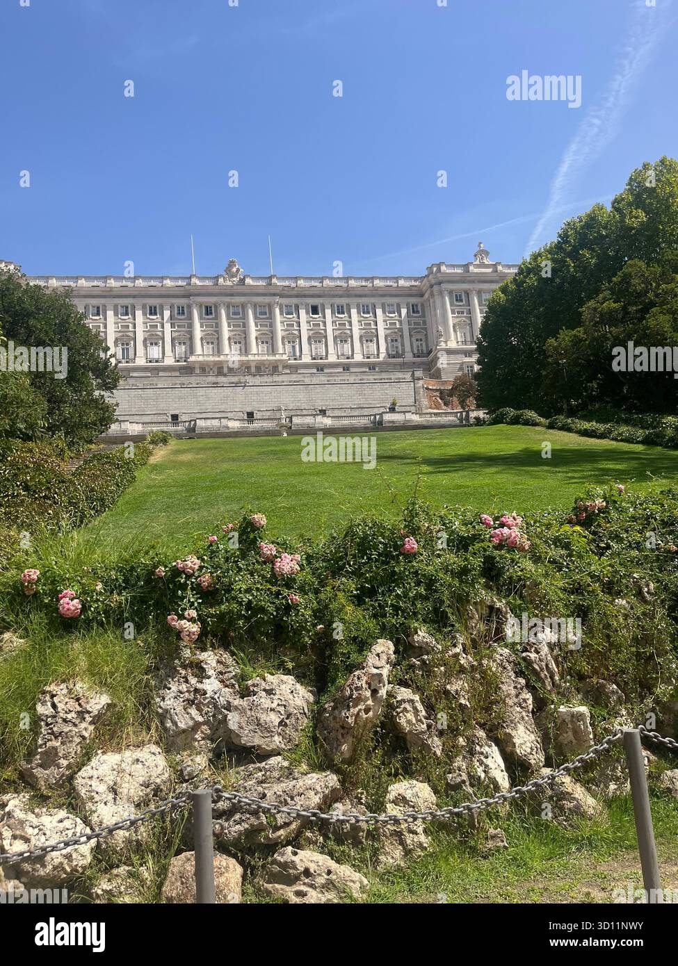 Aesthetic View of the Royal Palace of Madrid from Campo del Moro with Flowers, Trees, Greenery and a Clear Blue Sky on a Sunny Summer Day. - Smartphone Captured Stock Image