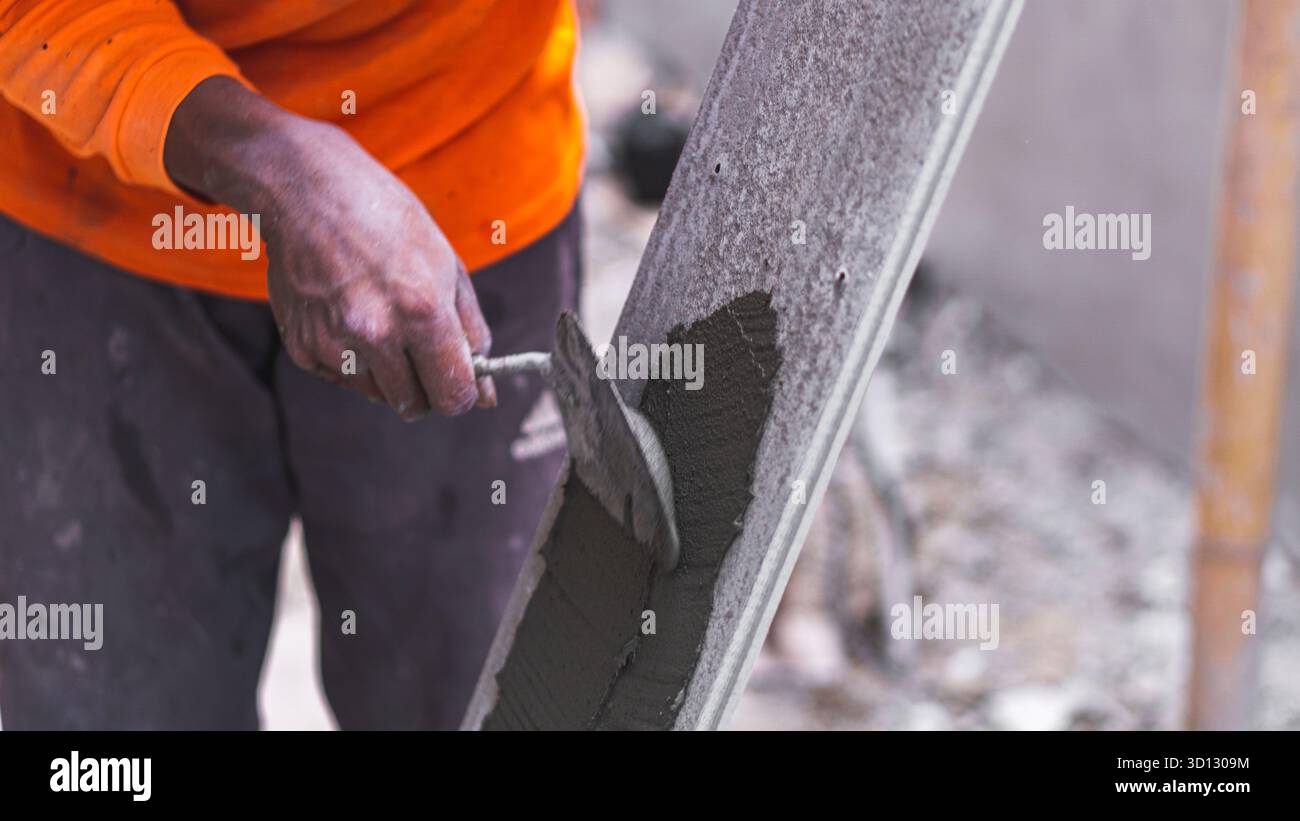 Composed Applying Worker applying Conwood adhesive on the wall, an essential step in ...