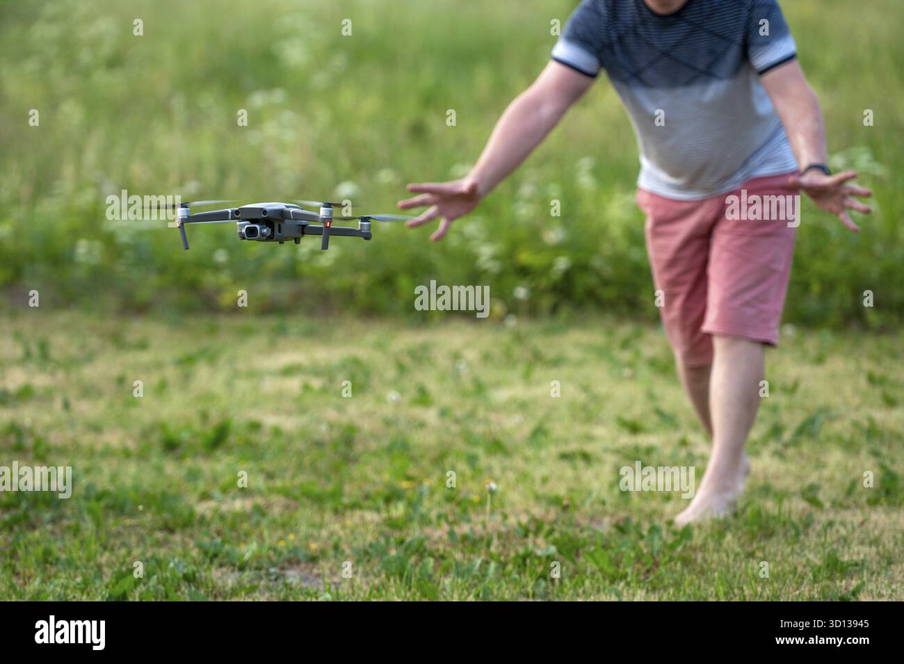 Drone quadcopter with digital camera flying over green grass. A man launches a drone Stock Photo