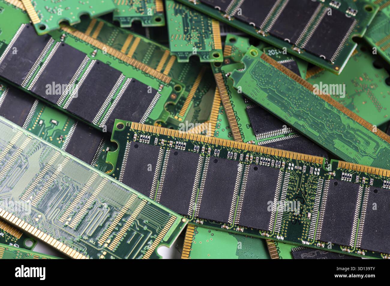 Various computer memory modules are piled on a green circuit board ...