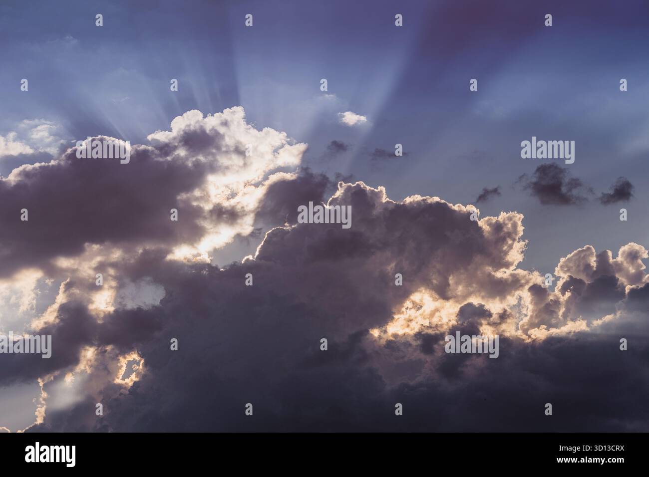 Dark cumulus clouds filling the sky, sunbeams piercing through silver linings, creating a beautiful moody atmosphere Stock Photo