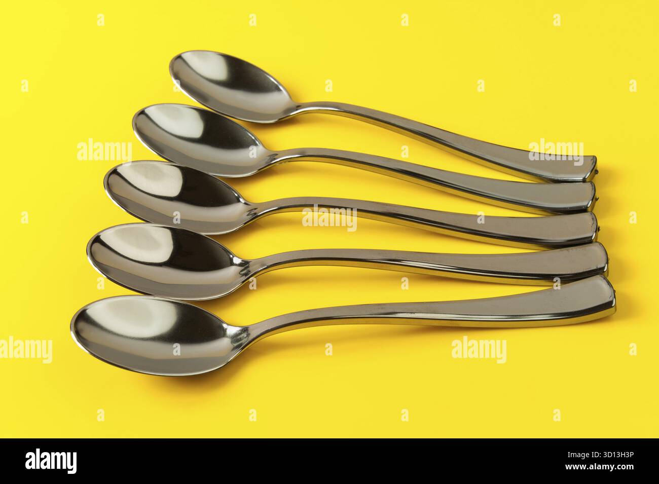 Plastic spoons painted under metal on a yellow background Stock Photo