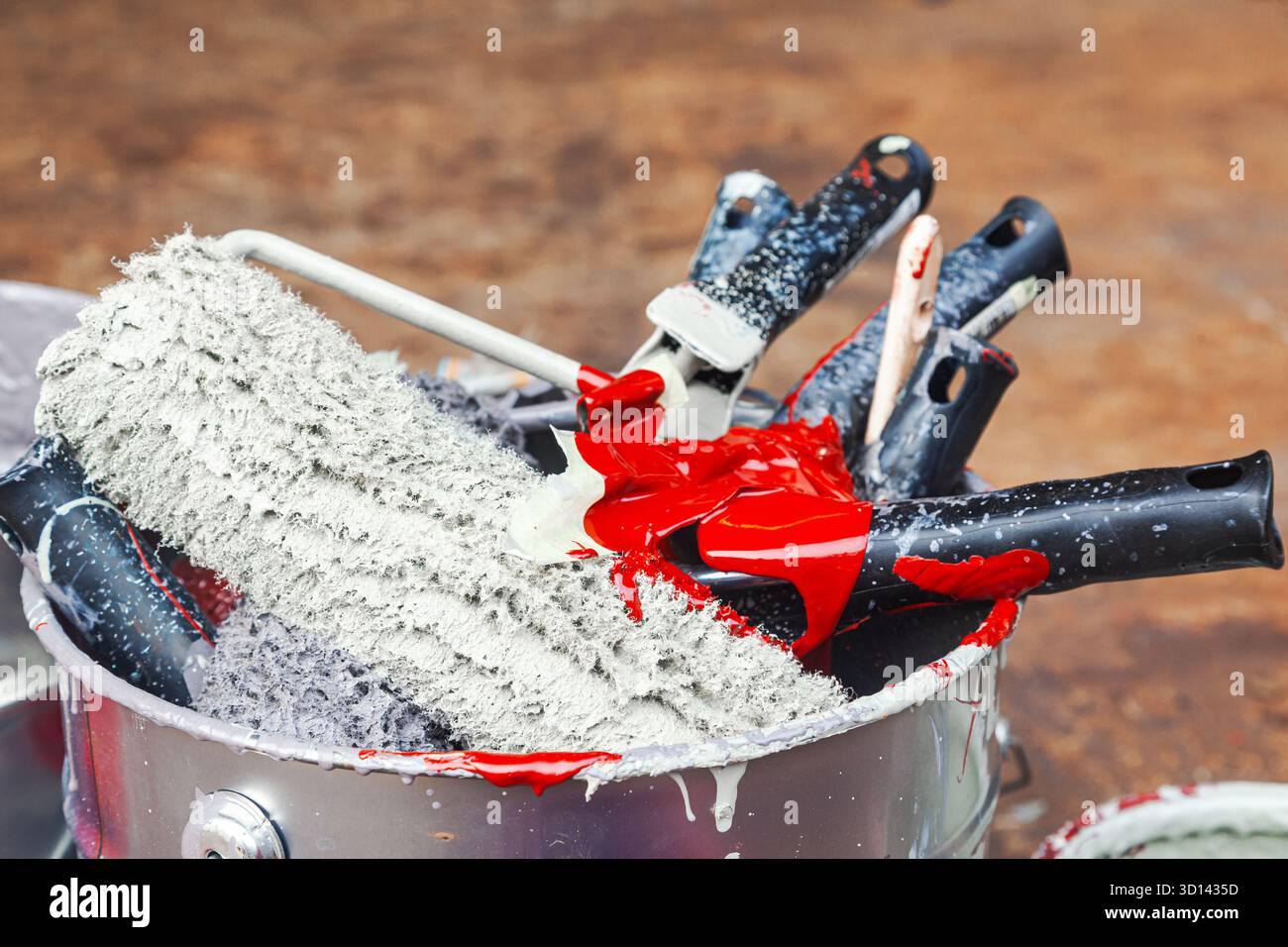 Empty paint buckets containing used rollers and brushes. Stock Photo
