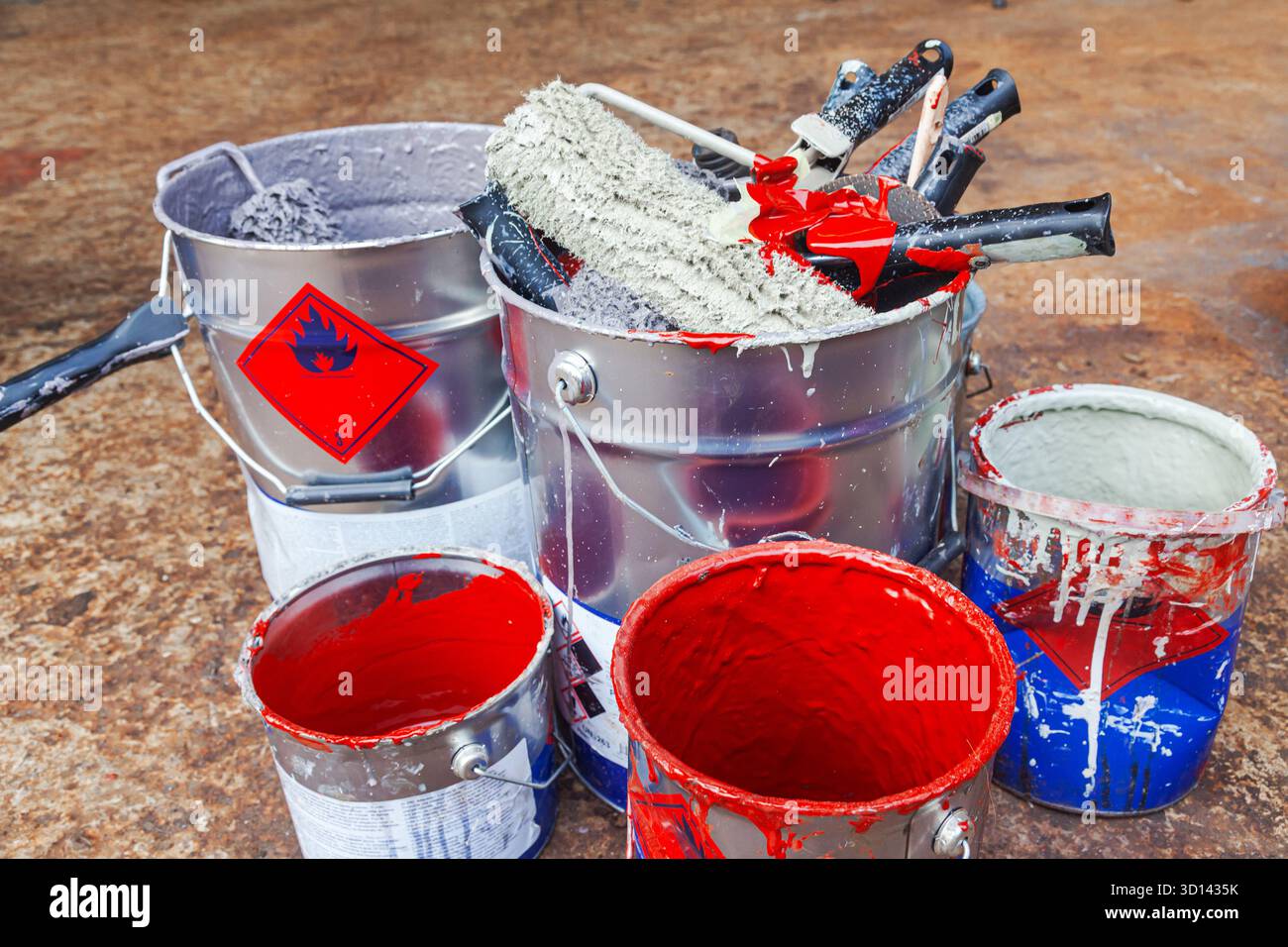 Empty paint buckets containing used rollers and brushes. Stock Photo