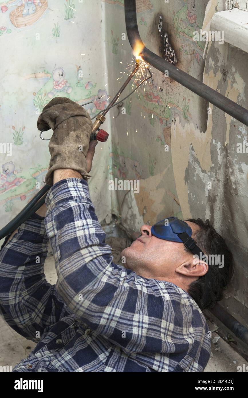 Installing new radiators with gas welding Stock Photo