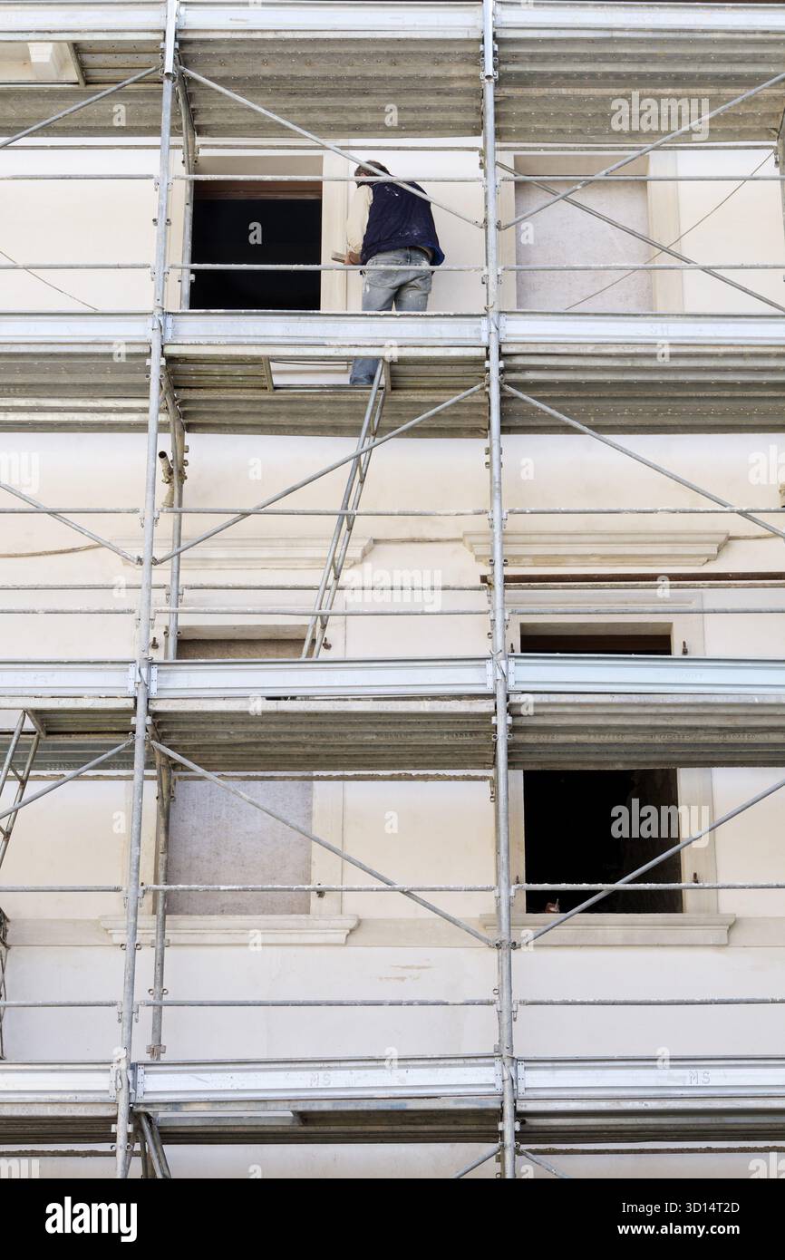 Bauarbeiter auf Baugeruest bearbeitet Hausfassade Stock Photo